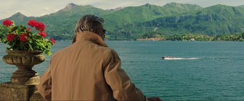 Movie still from “Casino Royale” (2006), directed by Martin Campbell – A man in a brown jacket looking out at a body of water; Medium shot, Over the shoulder angle