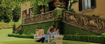 Movie still from “Casino Royale” (2006), directed by Martin Campbell – A man and a woman sitting on a lawn chair in front of a building; Wide shot, High angle