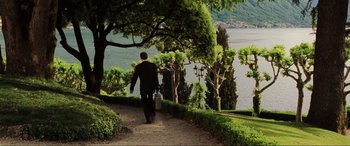 Movie still from “Casino Royale” (2006), directed by Martin Campbell – A man walking down a path next to a body of water; Wide shot, High angle
