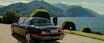 Movie still from “Casino Royale” (2006), directed by Martin Campbell – A man standing next to a car near a body of water; Extreme Wide shot, Over the shoulder angle