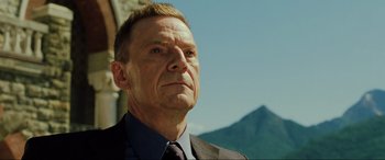 Movie still from “Casino Royale” (2006), directed by Martin Campbell – An older man in a suit and tie looking into the distance; Close Up shot, Low angle