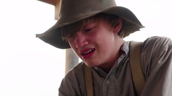 Movie still from “Catch the Bullet” (2021), directed by Michael Feifer – A young man wearing a hat and a brown hat; Close Up shot, High angle