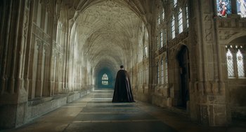 A man in a black cape standing in a hallway