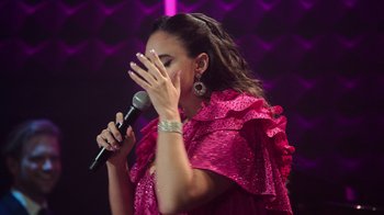 Movie still from “Catherine Cohen: The Twist...? She's Gorgeous” (2022), directed by Steven Brill – A woman holding a microphone up to her face; Close Up shot, High angle