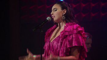 Movie still from “Catherine Cohen: The Twist...? She's Gorgeous” (2022), directed by Steven Brill – A woman in a pink dress singing into a microphone; Close Up shot, Low angle