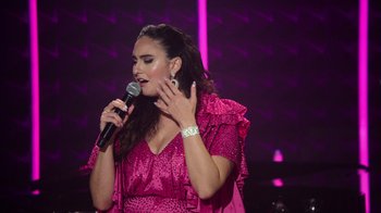 Movie still from “Catherine Cohen: The Twist...? She's Gorgeous” (2022), directed by Steven Brill – A woman in a pink dress is holding a microphone; Close Up shot, Over the shoulder angle