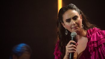 Movie still from “Catherine Cohen: The Twist...? She's Gorgeous” (2022), directed by Steven Brill – A woman holding a microphone in front of a crowd; Close Up shot, Over the shoulder angle