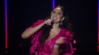 Movie still from “Catherine Cohen: The Twist...? She's Gorgeous” (2022), directed by Steven Brill – A woman in a pink dress holding a microphone and singing; Close Up shot, Low angle
