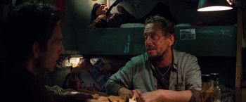 Movie still from “The Secret Life of Walter Mitty” (2013), directed by Ben Stiller – A man sitting at a table with a guitar in front of him; Medium shot, Over the shoulder angle