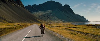 Movie still from “The Secret Life of Walter Mitty” (2013), directed by Ben Stiller – A man riding a bike down the side of a road; Extreme Wide shot, Low angle