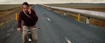 Movie still from “The Secret Life of Walter Mitty” (2013), directed by Ben Stiller – A man riding a bike down the side of a road; Wide shot, High angle