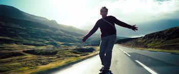 Movie still from “The Secret Life of Walter Mitty” (2013), directed by Ben Stiller – A man riding a skateboard down the side of a road; Wide shot, Low angle