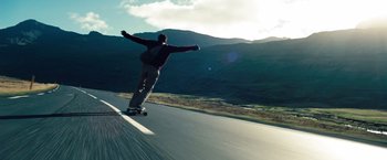 Movie still from “The Secret Life of Walter Mitty” (2013), directed by Ben Stiller – A man riding a skateboard down the side of a road; Wide shot, Low angle