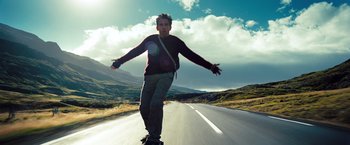 Movie still from “The Secret Life of Walter Mitty” (2013), directed by Ben Stiller – A man riding a skateboard down the side of a road; Medium shot, Low angle