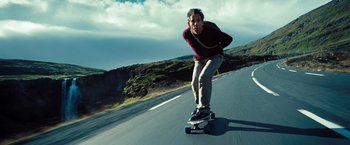 Movie still from “The Secret Life of Walter Mitty” (2013), directed by Ben Stiller – A man riding a skateboard down the side of a road; Medium shot, Low angle