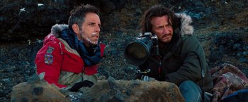 Movie still from “The Secret Life of Walter Mitty” (2013), directed by Ben Stiller – Two men sitting on the ground with a camera on their shoulder; Medium shot, Over the shoulder angle