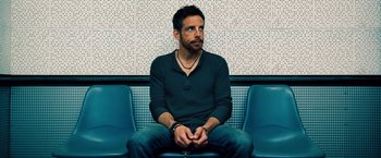 Movie still from “The Secret Life of Walter Mitty” (2013), directed by Ben Stiller – A man sitting on a bench with his hands in his pockets; Medium shot, Low angle