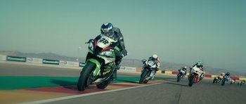 Movie still from “Centaur” (2022), directed by Daniel Calparsoro – Two motorcyclists are racing on a race track; Wide shot, High angle