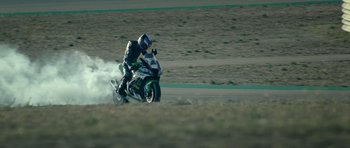 Movie still from “Centaur” (2022), directed by Daniel Calparsoro – A man riding a motorcycle down a dirt road; Extreme Wide shot, High angle