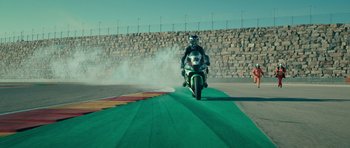 Movie still from “Centaur” (2022), directed by Daniel Calparsoro – A man riding a motorcycle down the side of a track; Extreme Wide shot, High angle