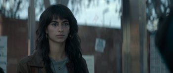 Movie still from “Centaur” (2022), directed by Daniel Calparsoro – A woman with long black hair standing in front of a building; Close Up shot, Over the shoulder angle