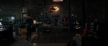 Movie still from “Centaur” (2022), directed by Daniel Calparsoro – A woman standing at a table in a room; Wide shot, High angle
