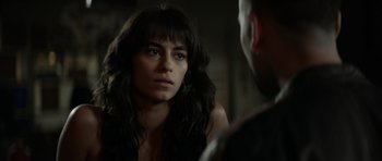 A woman looking into a mirror while standing next to a man