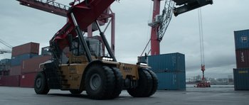 Movie still from “Centaur” (2022), directed by Daniel Calparsoro – A large yellow and black truck and some red containers; Wide shot, Low angle