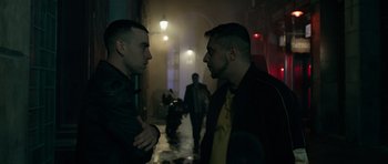Movie still from “Centaur” (2022), directed by Daniel Calparsoro – A couple of men standing next to each other on a street; Medium shot, Over the shoulder angle