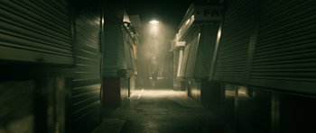 Movie still from “Centaur” (2022), directed by Daniel Calparsoro – A person walking down a street at night; Extreme Wide shot, High angle