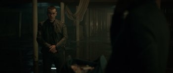 Movie still from “Centaur” (2022), directed by Daniel Calparsoro – A man standing in front of a mirror in a dark room; Medium shot, Over the shoulder angle