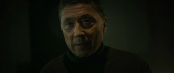 Movie still from “Centaur” (2022), directed by Daniel Calparsoro – An older man wearing a black shirt and a black jacket; Close Up shot, Low angle
