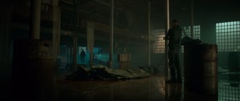 Movie still from “Centaur” (2022), directed by Daniel Calparsoro – A person standing in a dark room with a building in the background; Wide shot, Low angle