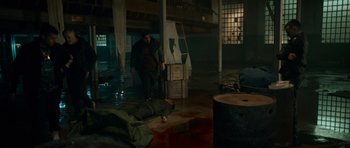 Movie still from “Centaur” (2022), directed by Daniel Calparsoro – A man standing next to an open door in a room; Wide shot, High angle