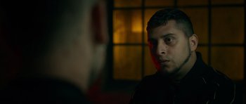 Movie still from “Centaur” (2022), directed by Daniel Calparsoro – A young man stares into the camera in front of a window; Close Up shot, Over the shoulder angle