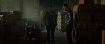 Movie still from “Centaur” (2022), directed by Daniel Calparsoro – Two men standing next to each other in a warehouse; Wide shot, Over the shoulder angle