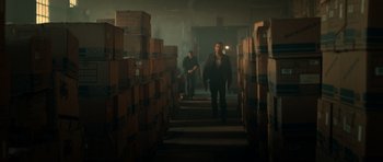 Movie still from “Centaur” (2022), directed by Daniel Calparsoro – Two men walking down the stairs in a warehouse; Wide shot, High angle