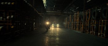 Movie still from “Centaur” (2022), directed by Daniel Calparsoro – A man riding a motorcycle down a street at night; Extreme Wide shot, Low angle