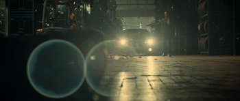 Movie still from “Centaur” (2022), directed by Daniel Calparsoro – A man standing next to a car in a garage; Wide shot, Low angle