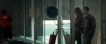 Movie still from “Centaur” (2022), directed by Daniel Calparsoro – A fire hydrant hanging on a wall next to a glass door; Medium shot, Over the shoulder angle