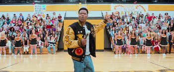 Movie still from “Central Intelligence” (2016), directed by Rawson Marshall Thurber – A man in black and yellow jacket standing in front of a crowd; Medium shot, Low angle