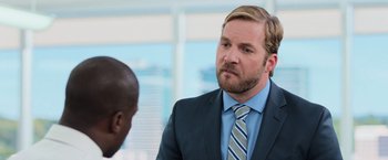 Movie still from “Central Intelligence” (2016), directed by Rawson Marshall Thurber – A man wearing a suit and tie talking to another man wearing a suit and tie; Close Up shot, Over the shoulder angle