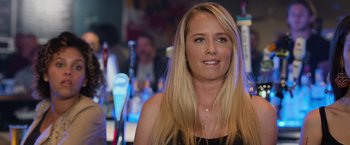 Movie still from “Central Intelligence” (2016), directed by Rawson Marshall Thurber – A beautiful blonde woman with long hair and blue eyes in a bar; Close Up shot, Over the shoulder angle