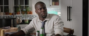 Movie still from “Central Intelligence” (2016), directed by Rawson Marshall Thurber – A man sitting at a table with a bottle in front of him; Close Up shot, Over the shoulder angle