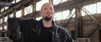 Movie still from “Central Intelligence” (2016), directed by Rawson Marshall Thurber – A man with a beard and a black jacket is smiling; Close Up shot, Low angle