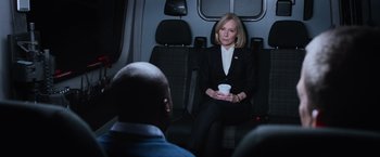Movie still from “Central Intelligence” (2016), directed by Rawson Marshall Thurber – A woman sitting on the back of a vehicle holding a cup; Medium shot, Over the shoulder angle