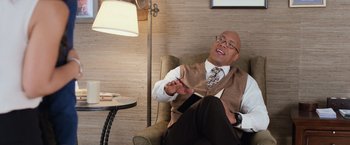 Movie still from “Central Intelligence” (2016), directed by Rawson Marshall Thurber – A man sitting in a chair wearing a vest and a tie; Medium shot, Over the shoulder angle