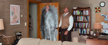 Movie still from “Central Intelligence” (2016), directed by Rawson Marshall Thurber – A man standing in front of a door with duct tape on it; Wide shot, Over the shoulder angle