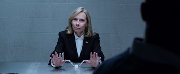 Movie still from “Central Intelligence” (2016), directed by Rawson Marshall Thurber – A woman sitting at a table in front of a brick wall; Medium shot, Over the shoulder angle
