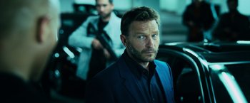 Movie still from “Central Intelligence” (2016), directed by Rawson Marshall Thurber – A person wearing a suit holding a gun; Close Up shot, Low angle